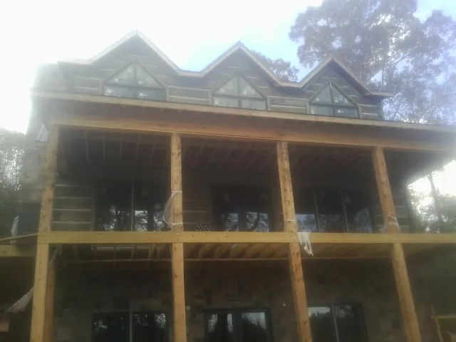 Dormers and porch framing on a large log home under construction — Roof Coating work by our crew in Harris